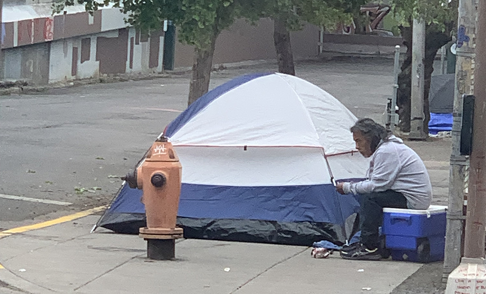 homeless man next to tent in old town